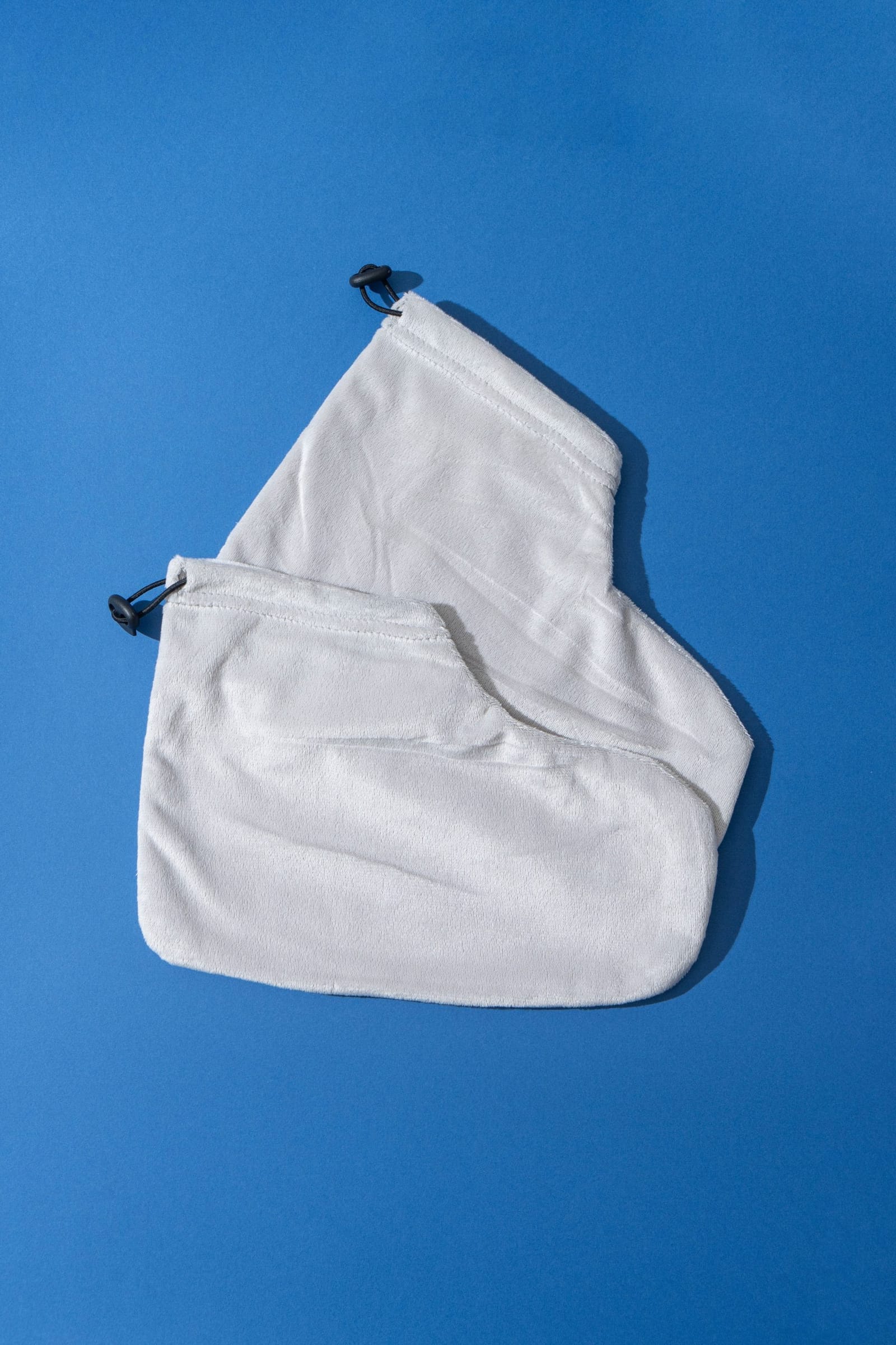 A pair of reusable terry cloth foot covers with drawstring closures