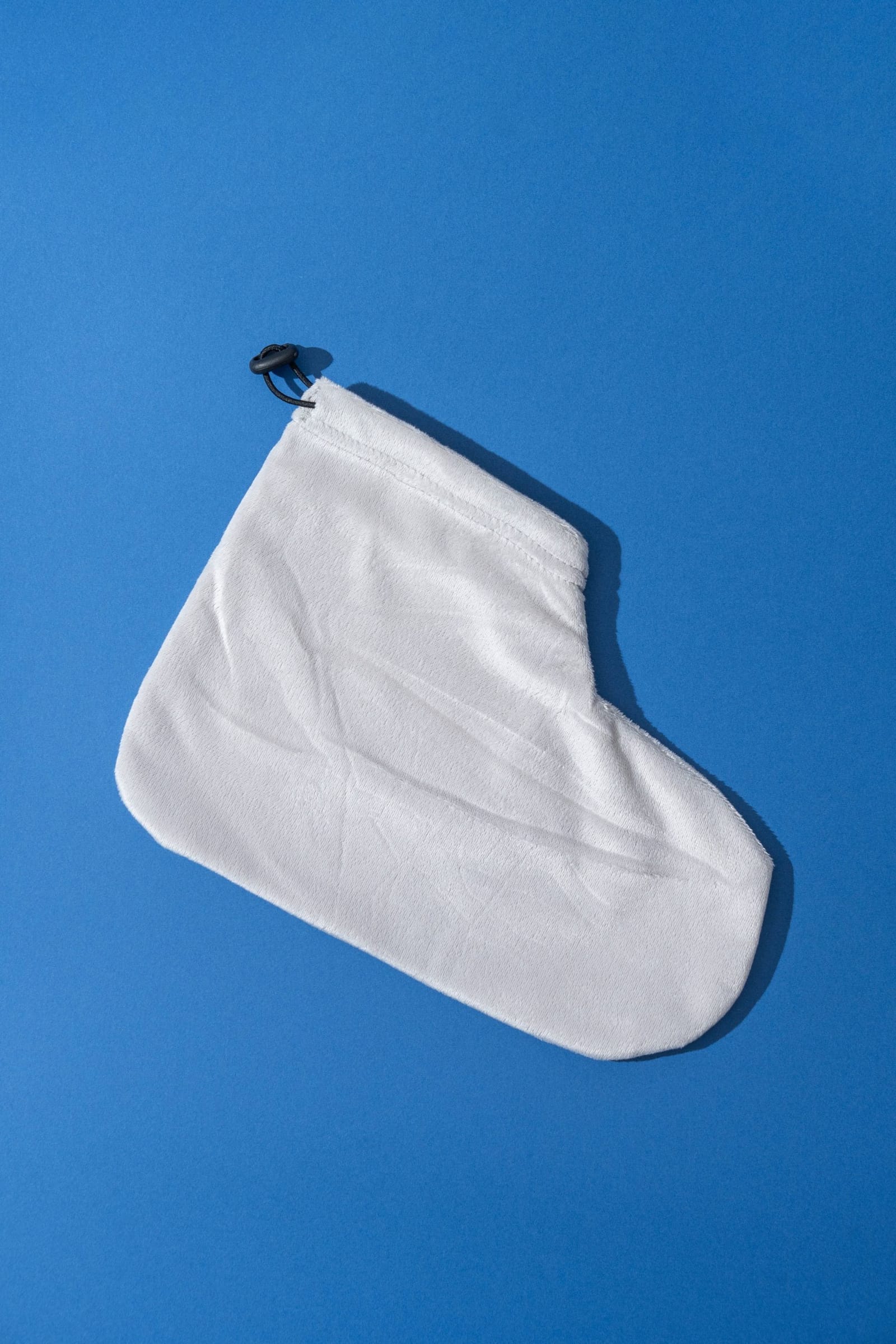A single reusable terry cloth foot cover, drawstring closure at the ankle