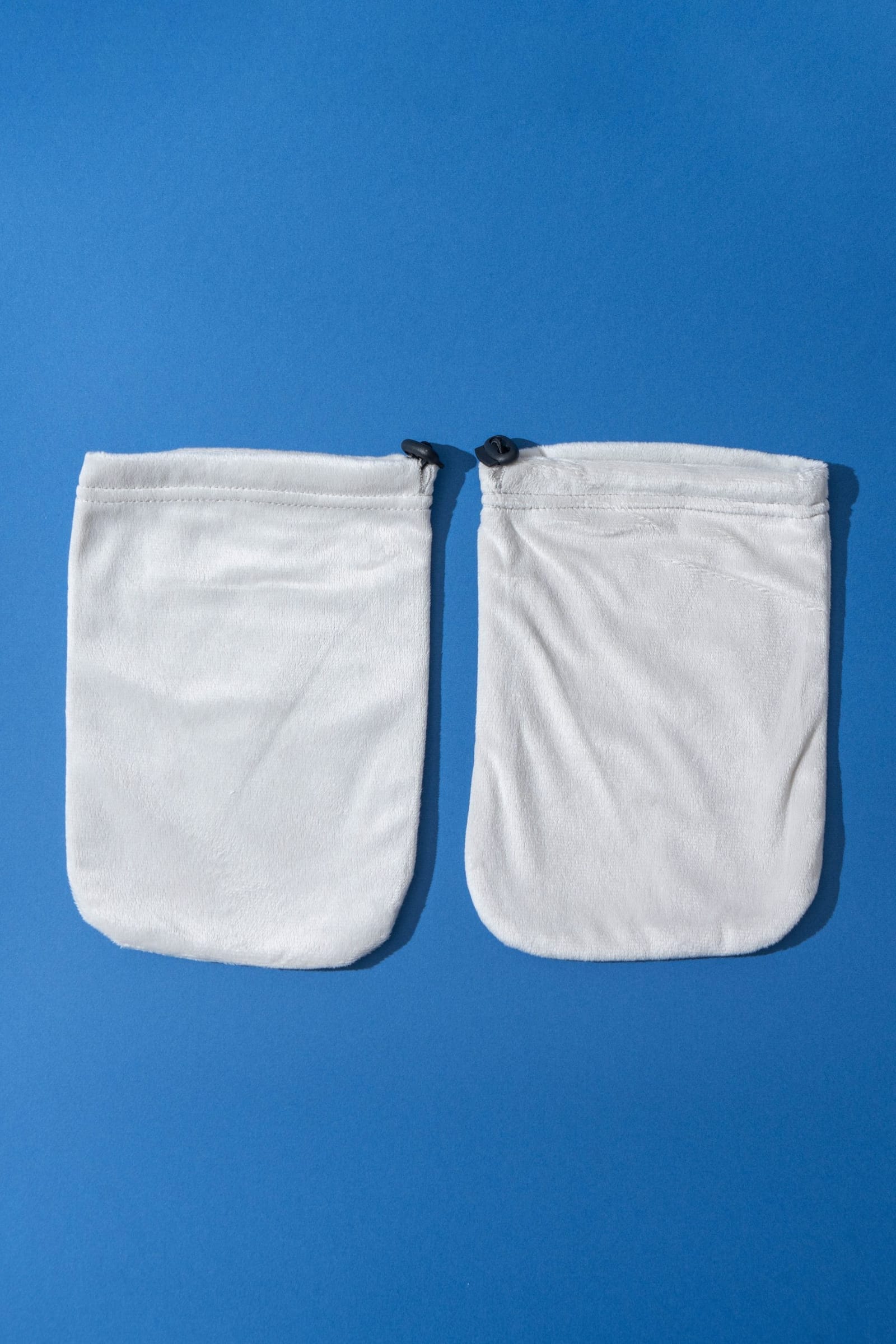 A pair of reusable terry cloth hand covers with drawstring closures