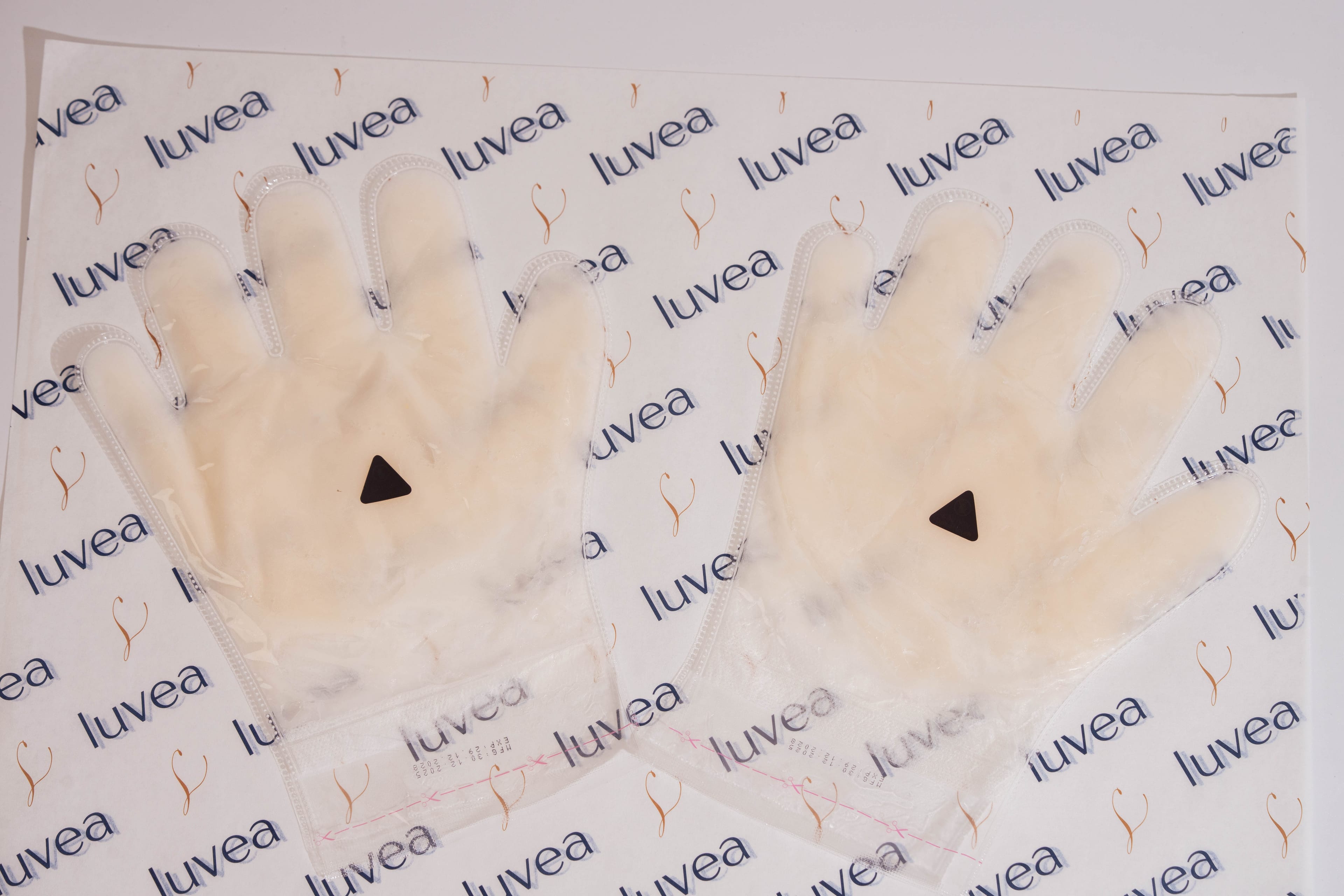 Glove-shaped paraffin wax masks laid flat on luvéa branded paper