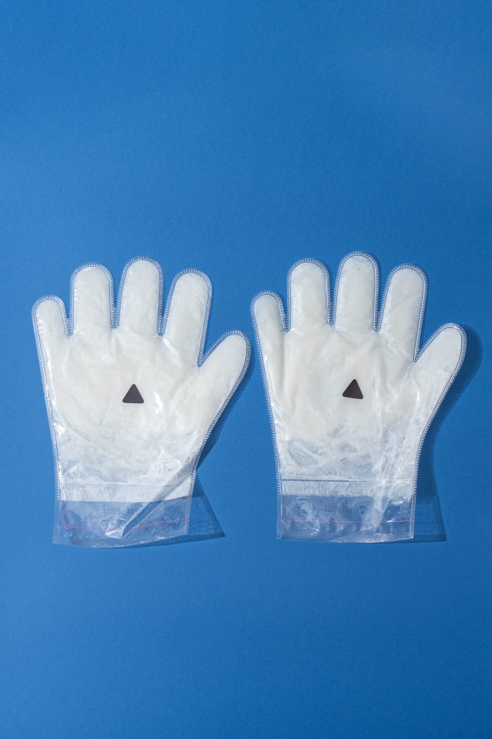 A pair of glove-shaped paraffin beauty wax hand masks in their sealed packs